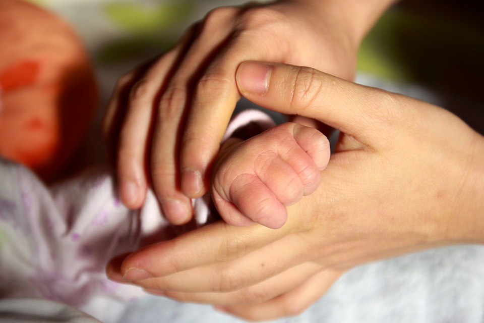 mano de bebé entre manos de adulto