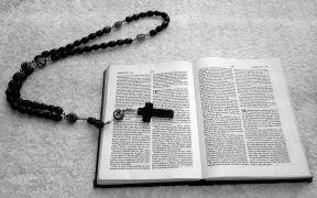 Biblia en blanco y negro con un rosario de madera encima utilizada y leída mientras se realiza un exorcismo