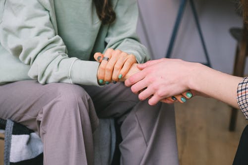 Dos mujeres sosteniendo sus manos en una atención psicológica de psicoterapia feminista